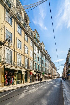 Una calle con edificios, tiendas y una línea de tranvía.