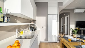 Eine moderne Küche mit Kühlschrank, Spüle und einem Essbereich mit Tisch für zwei Personen.