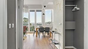 Ein modernes Interieur mit Holzboden, einem Essbereich mit Stühlen und Tisch sowie einer Aussicht durch große Fenster.