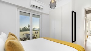 Ein Hotelzimmer mit einem Bett, einer gelben Tagesdecke, einem großen Spiegel und einer Schiebetür zum Balkon.