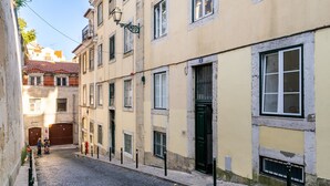 A narrow cobblestone street lined with historic buildings, featuring a mix of residential and commercial properties. - Sé Skyline Apartment (Lisbon)