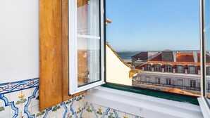 A window with a view of buildings and a clear sky. - Sé Skyline Apartment (Lisbon)