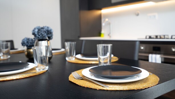 Une cuisine moderne avec des plans de travail noirs, un pare-feu blanc et des appareils en acier inoxydable.