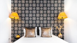 Un lit bien fait, avec une tête de lit à motifs, deux lampes de chevet et un vase décoratif posé sur la table de chevet.