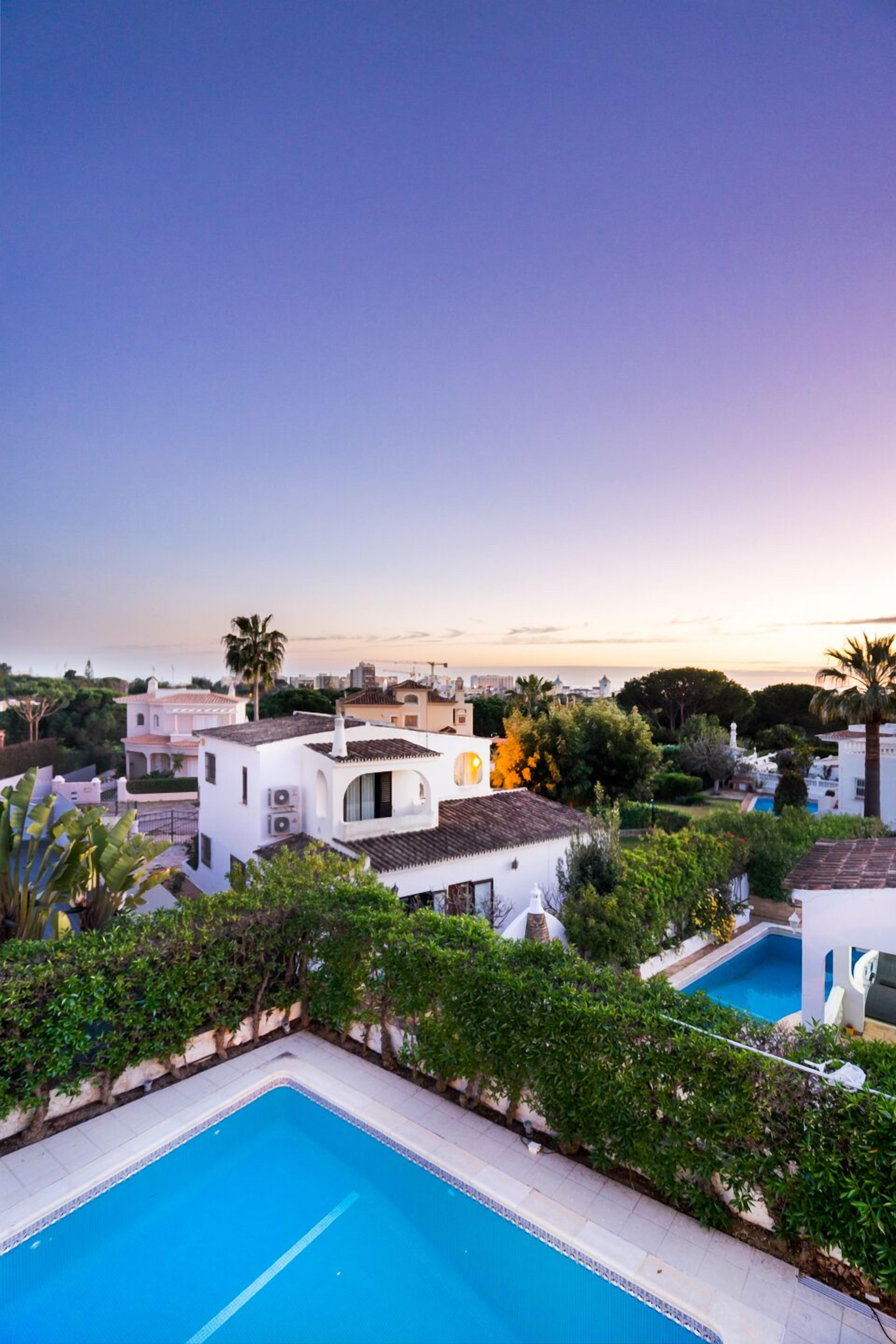 A residential area with a swimming pool surrounded by lush greenery and white buildings.