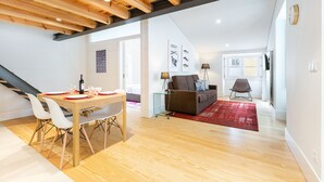 Um espaço moderno para relaxar com área de jantar, sofá e tapete vermelho.