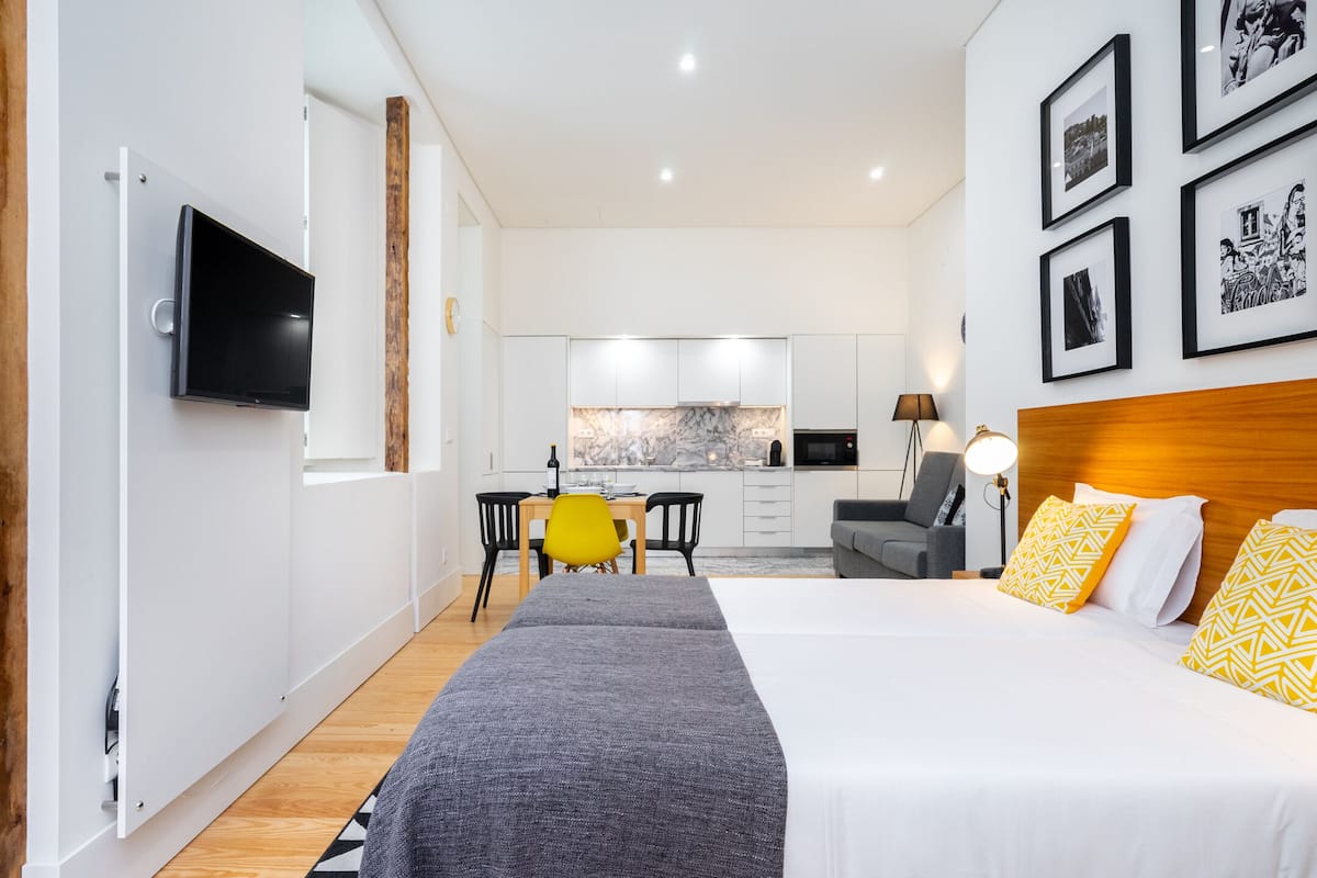 Ein modernes Hotelzimmer mit einem großen Bett, einem Fernseher, einer Essecke und einer Küche.