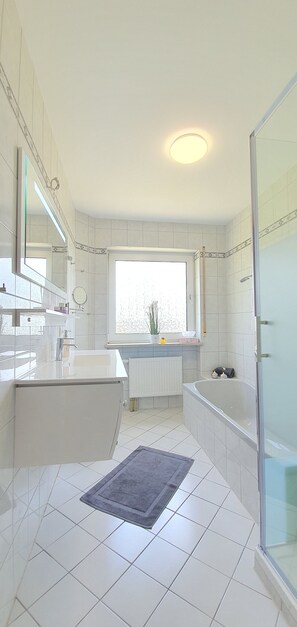 Een bad/douchecombinatie, een haardroger, handdoeken, zeep