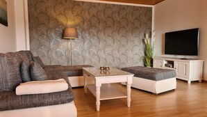 Un salon comprenant un canapé, une table basse, une lampe, un téléviseur et un meuble.