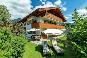 Relax in a serene garden with lounge chairs and a dining set, surrounded by mountains.
