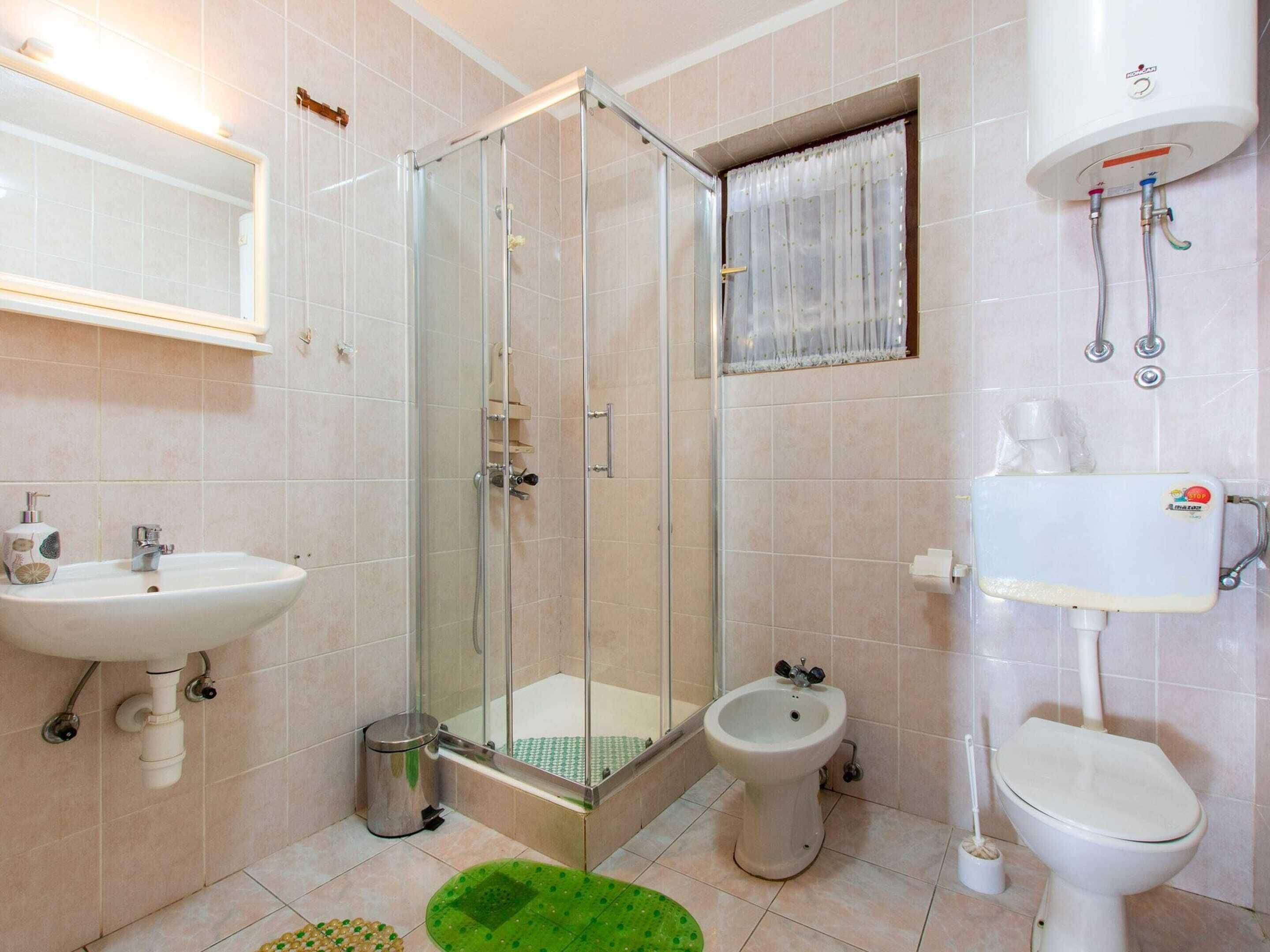 A bathroom with a glass-enclosed shower, a bidet, a toilet, and a sink.