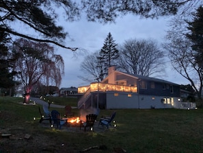 Een huis met een vuurkuil in de tuin, omringd door stoelen.