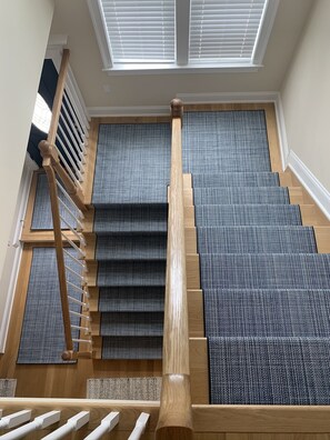 Staircase with a patterned carpet and a window above.