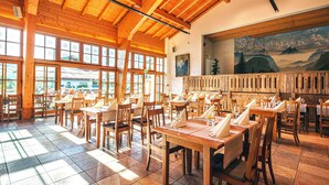 A restaurant with wooden interiors, large windows, and a mountain view mural. - Family suite with 2 bedrooms 45 sqm (Inzell)