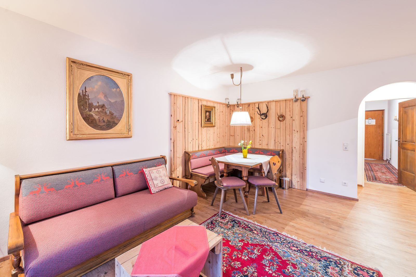 A cozy living room with a sofa, a dining table, and a rug.