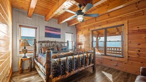 A log cabin bedroom with a wooden bed, a ceiling fan, and large windows. - AMAZING VIEW MANOR! Perfect for Weddings and Reunions! (Sevierville)