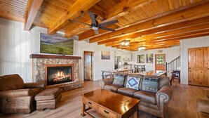 A spacious living room with a stone fireplace, leather furniture, wooden beams, and a large painting on the wall. - AMAZING VIEW MANOR! Perfect for Weddings and Reunions! (Sevierville)