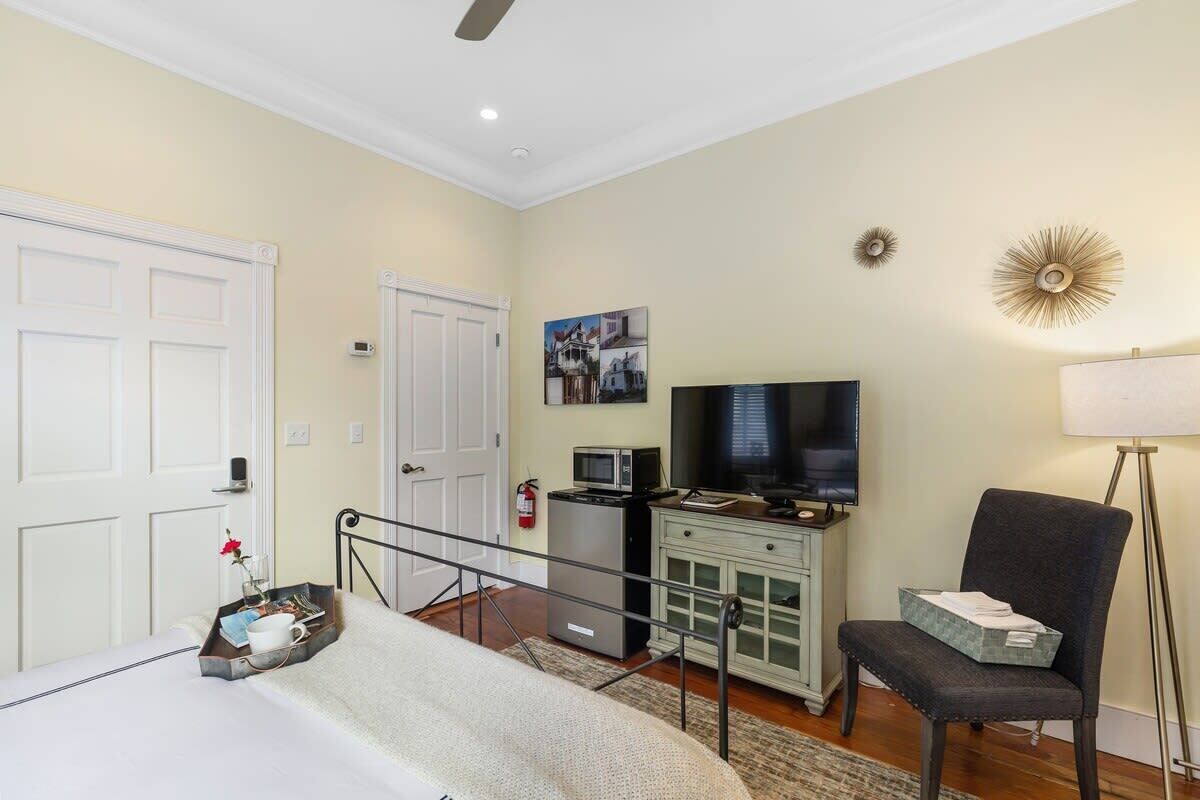 A hotel room with a bed, a desk with a computer, a TV, a chair, and a lamp.