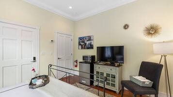 A hotel room with a bed, a desk with a computer, a TV, a chair, and a lamp.