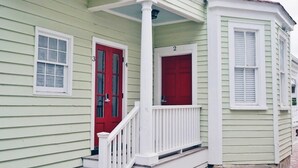 A green house with two red doors, white railings, and a brick pathway. - Cozy Suite in Downtown Charleston with HEATED POOL (Charleston)