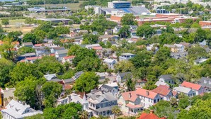 Zona residencial con casas, un estadio y un cuerpo de agua al fondo.