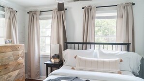 A bedroom with a bed, a bedside table, a lamp, and curtains. - Beautifully Restored  Downtown Apartment (Charleston)
