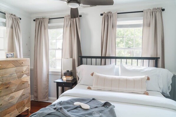 A bedroom with a bed, a nightstand, a lamp, and a dresser.