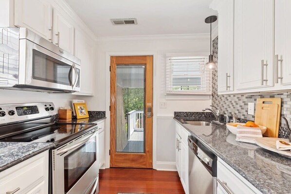A modern kitchen with white cabinets, a stainless steel microwave, a built-in oven, and a granite countertop.