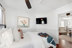 Ein Schlafzimmer mit Bett, Fernseher und einem Bild an der Wand.
