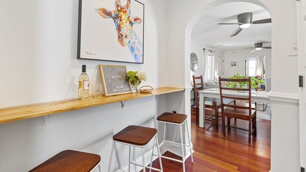 A modern interior with a wooden bar area, a giraffe painting, and a view into a dining room. - Beautifully Restored  Downtown Apartment (Charleston)