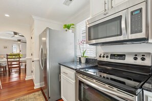 A modern kitchen with stainless steel appliances, white cabinetry, and a dining area with a wooden table and chairs.