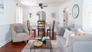 A living room with a sofa, armchair, coffee table, and dining table with chairs. - Beautifully Restored  Downtown Apartment (Charleston)