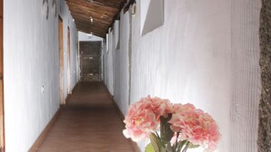 A corridor with a tiled floor, wooden ceiling beams, and a wall-mounted clock. - Complejo Rural Puente Romano (Orgaz)