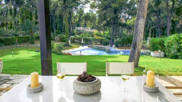Una mesa con velas y copas de vino, con vistas a una piscina y un jardín.