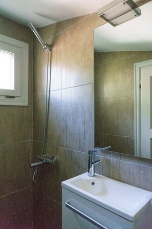 Un baño con ducha, lavamanos y espejo.