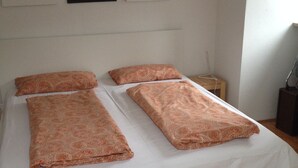Ein Bett mit weißer Bettdecke und drei Kissen mit Muster.