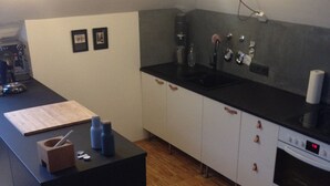 Eine moderne Küche mit schwarzem Arbeitsplatz, weißen Schränken, einem Einbauofen und einer Kaffeemaschine.