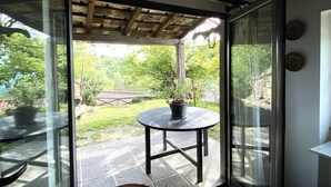 Puerta de cristal que da a un patio exterior con una mesa redonda y una planta en maceta.