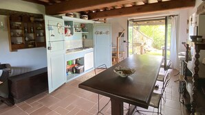 Una cocina rústica con vigas de madera a la vista, una mesa de comedor y un refrigerador empotrado.