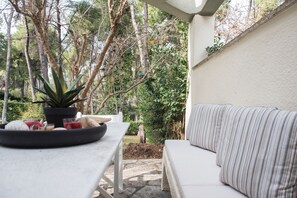 A patio area with a white table and a white sofa, surrounded by trees and greenery. - Villa Armonia by halu! Villas (Kassandra)