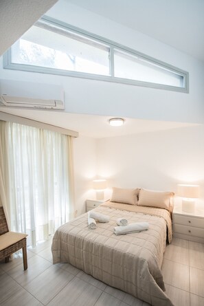 A bedroom with a large bed, two bedside lamps, a window, and a chair. - Villa Armonia by halu! Villas (Kassandra)