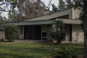 A modern house with a covered patio, a stone fireplace, and a small garden. - Villa Armonia by halu! Villas (Kassandra)