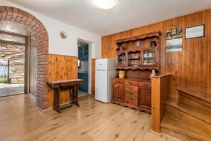 Enjoy cooking in this kitchen with refrigerator and wooden cabinetry, adjacent to a doorway leading to an outdoor area.