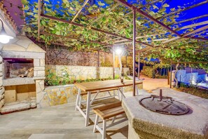 Relax under the shade of a lush pergola, surrounded by a serene stone wall and a tranquil well.