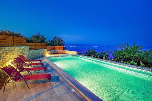Relax by the serene pool, surrounded by lounge chairs and breathtaking views of the sea and city.