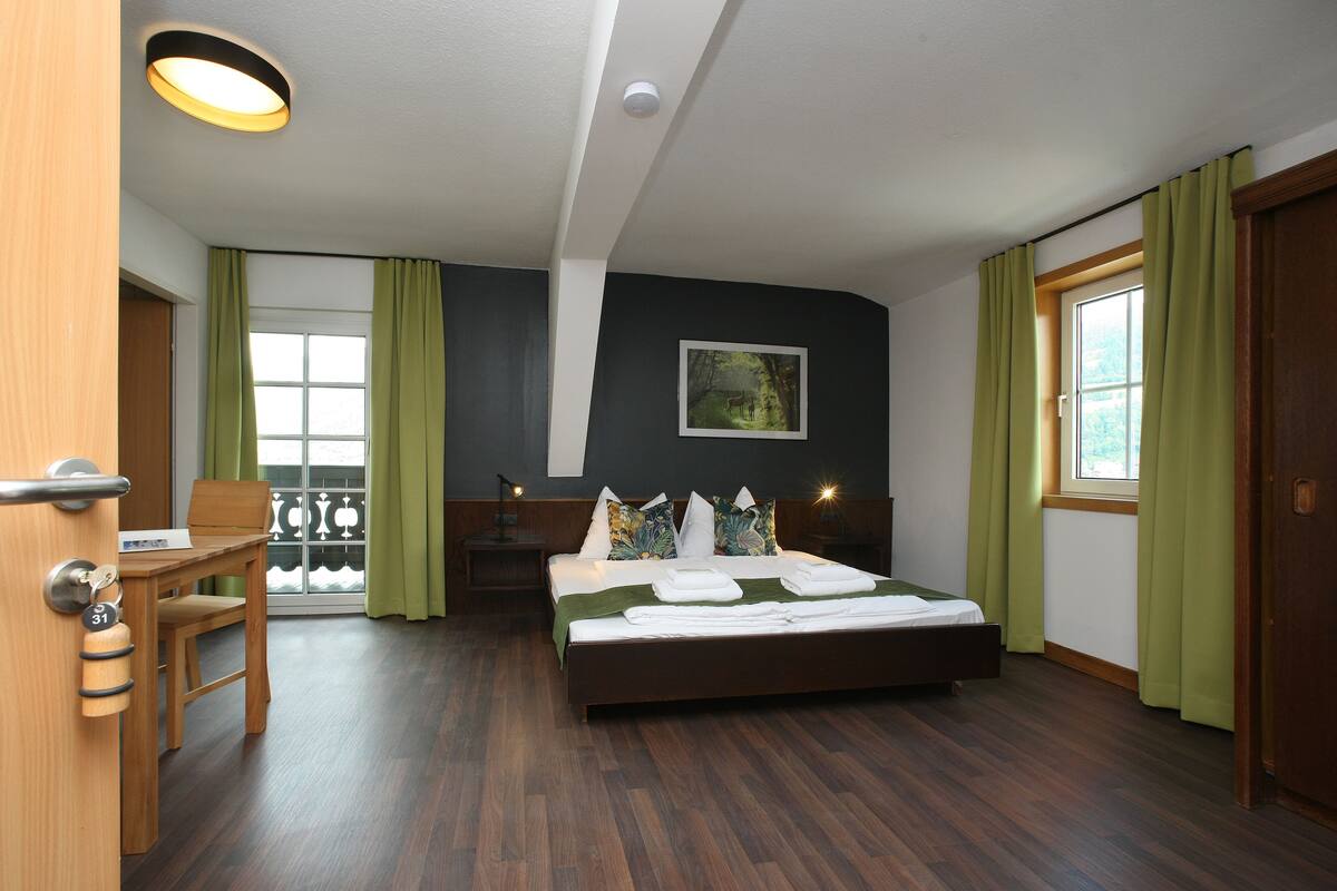 A bedroom with a bed, a desk, and a chair.