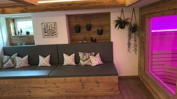 Un moderno salón con un banco de madera, un jarrón de plantas en la pared y un rincón iluminado en morado.