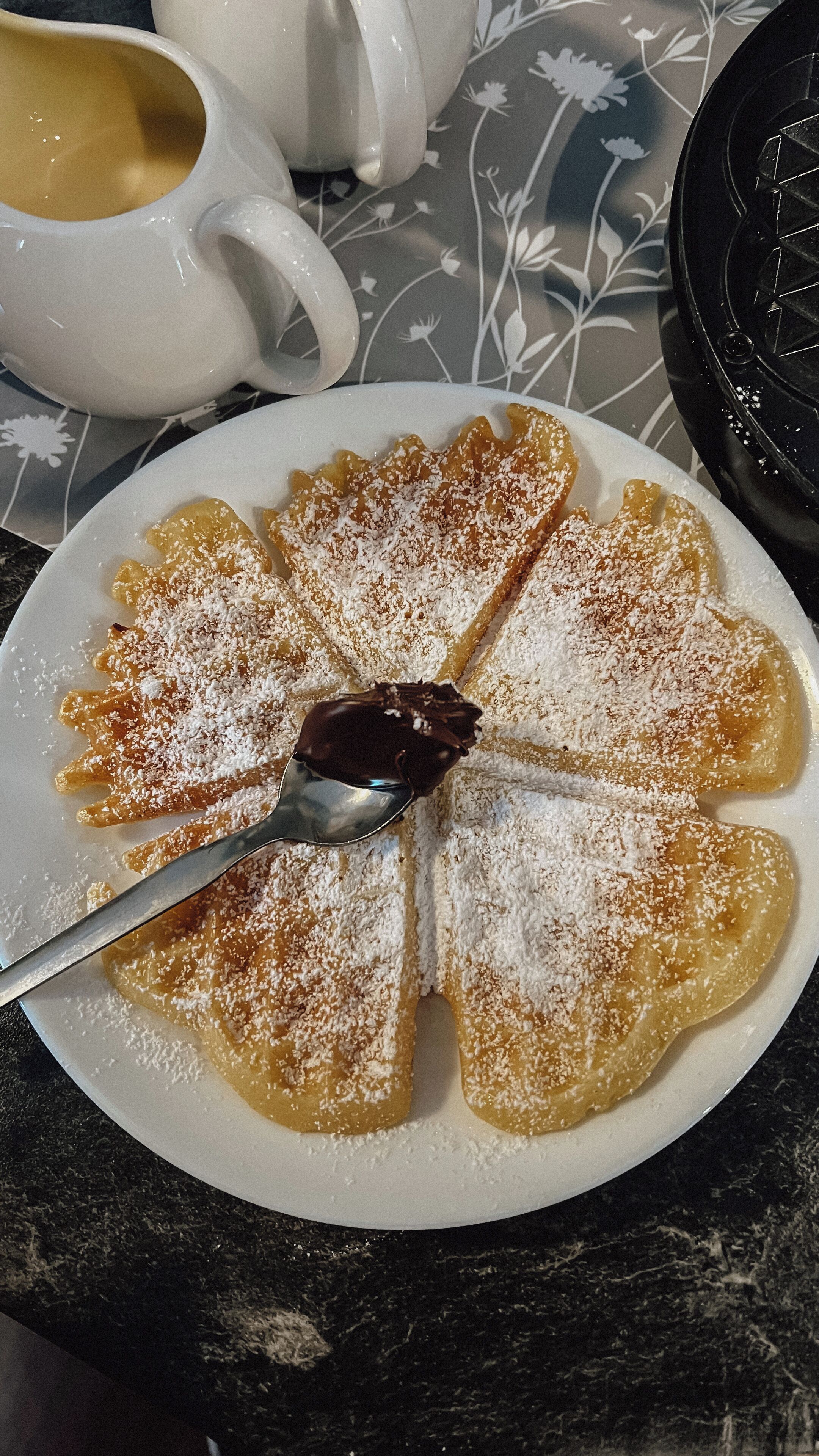 A plate of dessert with powdered sugar and a spoon.