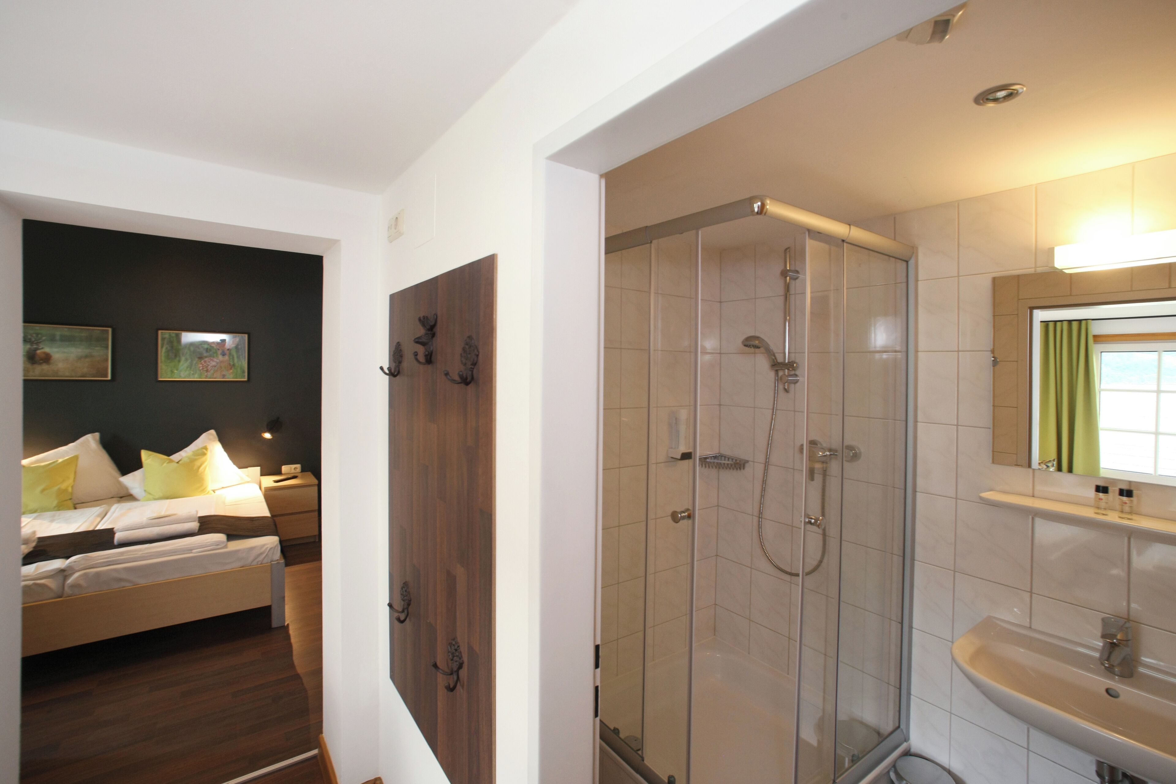 A modern hotel room with a bed, bedside table, and a glass-enclosed shower area.