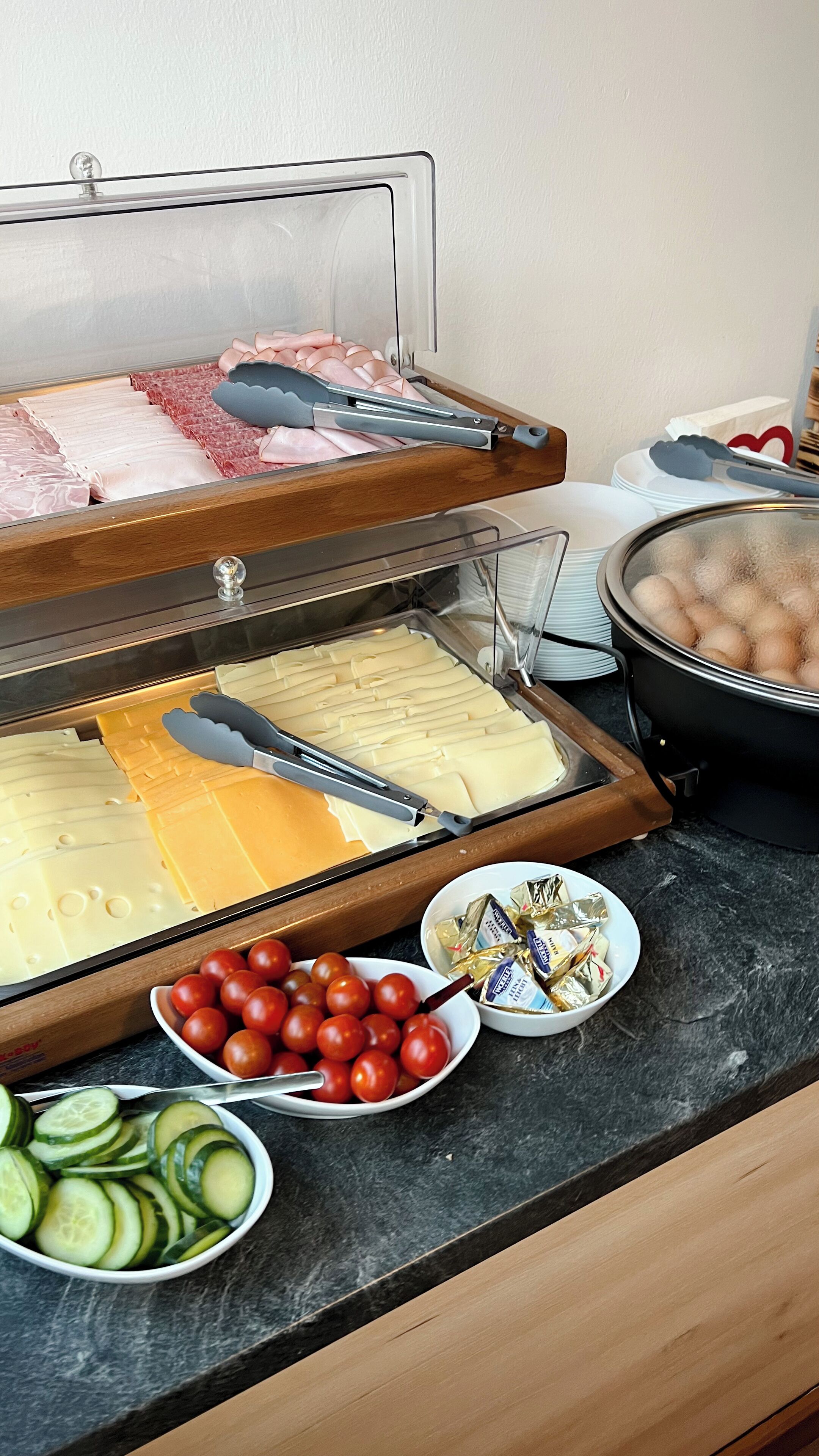 A buffet setup with various food items including sliced meats, cheeses, and vegetables.